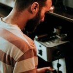 A barista prepares coffee using a machine